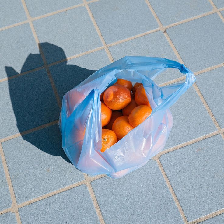 A blue shopping bag filled with tangerines
