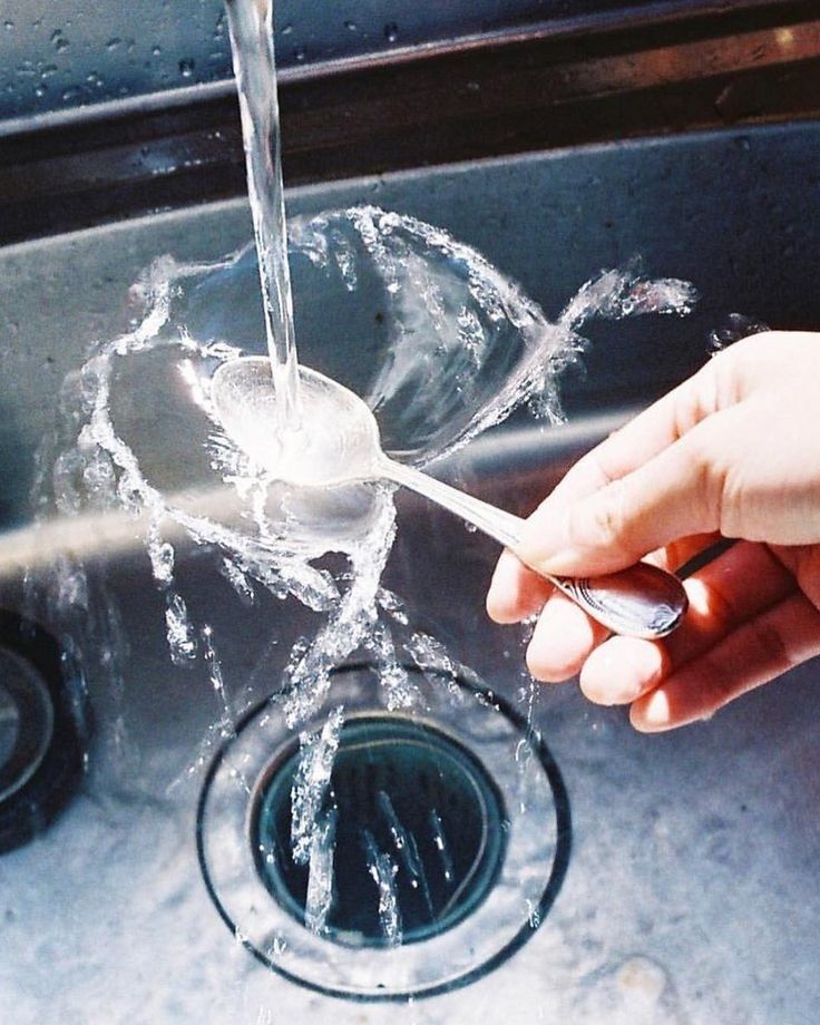 A spoon being rinsed under running water